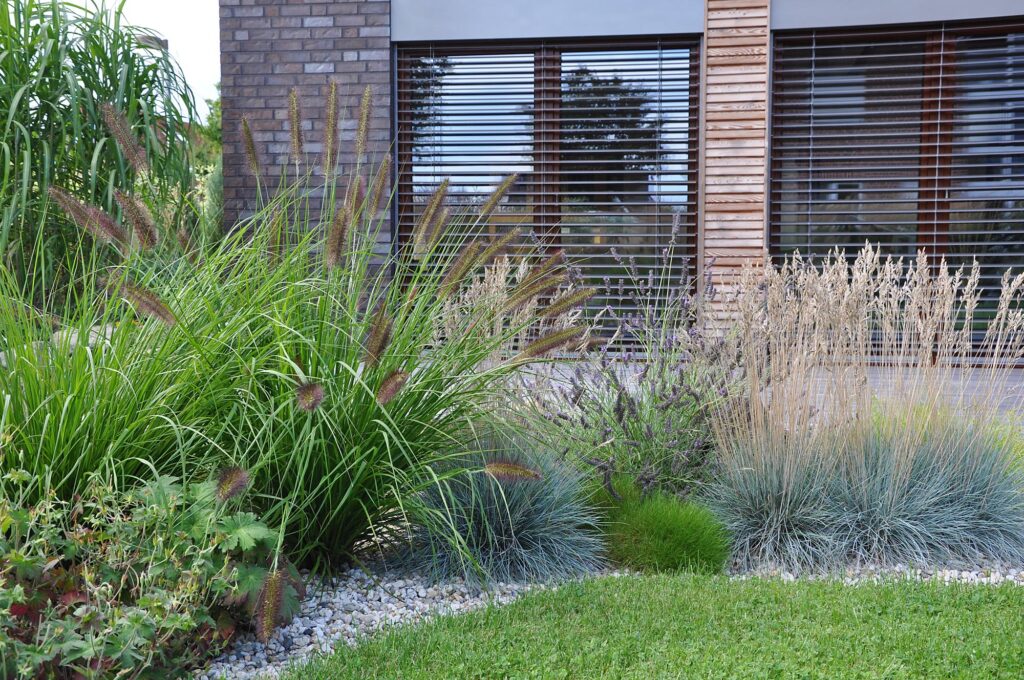 Dieser modern gestaltete Garten mit Ziergräsern und kleinen Sträuchern, eingefasst von Kieselsteinen, zeigt anschaulich, wie professionelle Gartenplanung oder Pflanzplanung für Gärten in Bocholt, Kreis Borken oder dem Münsterland aussehen kann.